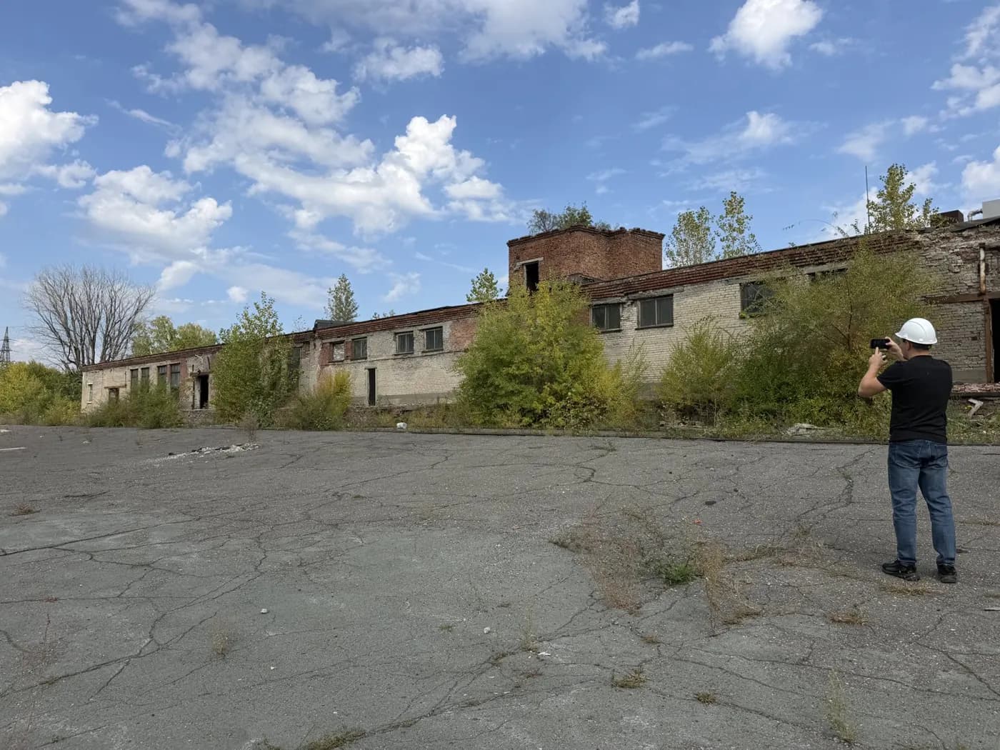 Инженер снимает промышленную площадку и корпус с трещинами в покрытии