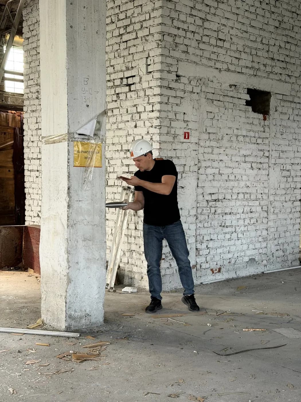 Инженер осматривает кирпичную стену цеха с трещинами